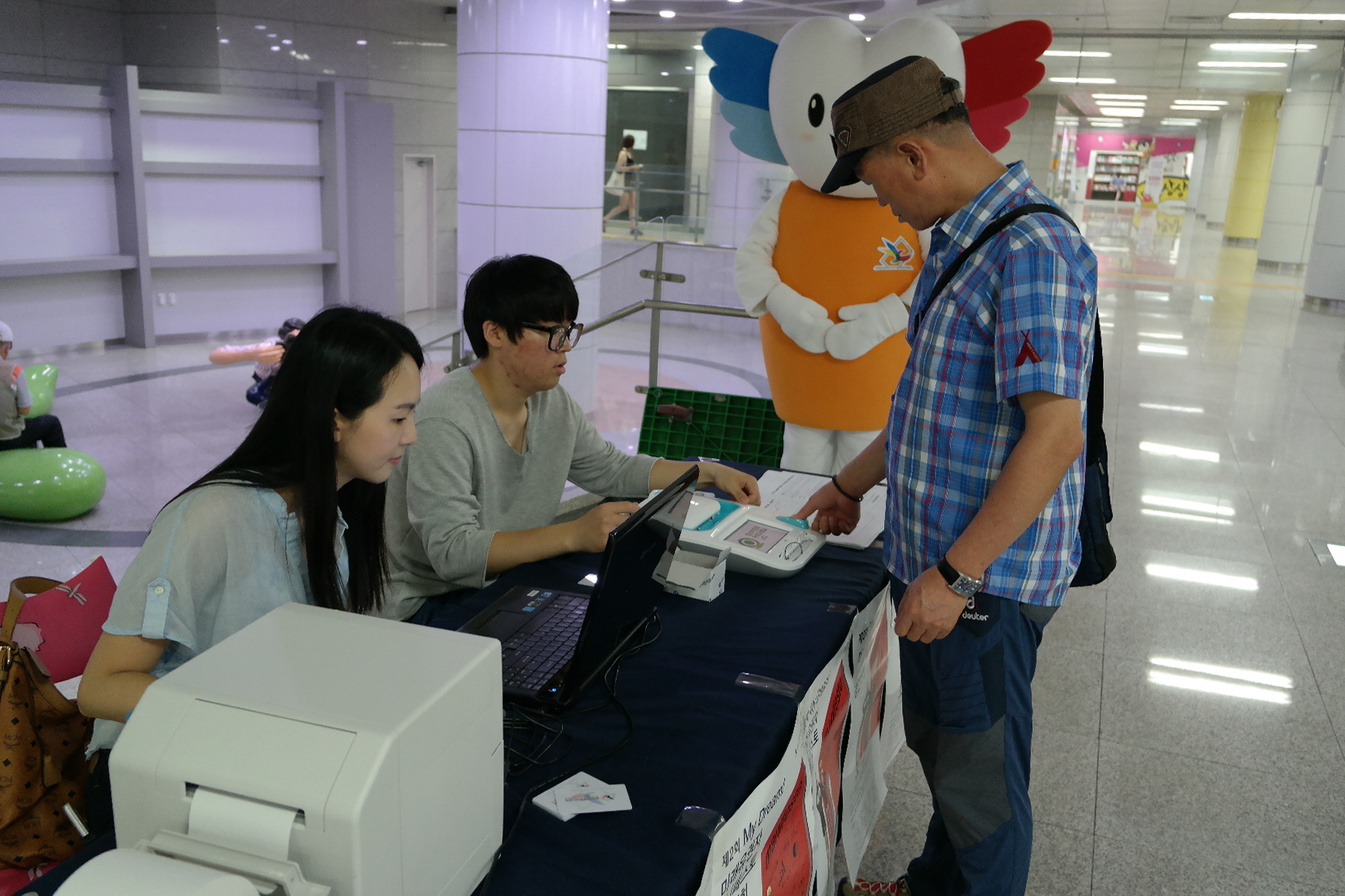 체험도우미의 안내에 따라 본인확인기에 지문으로 본인확인을 하는 모습입니다.