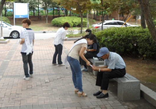 이미지 내용은 시민들에게 선거관련 과태료 및 포상금 규정을 설명해주는 위원회 직원들의 모습입니다.