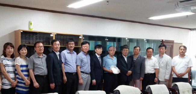 명예퇴직 직원에게 재직기념패 수여 후 위원 및 직원 전체 기념사진 촬영한 모습