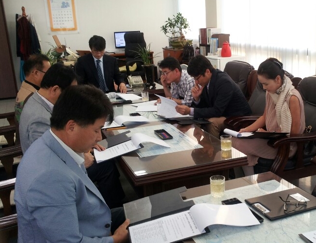 용인시수지구선거관리위원회 위원장, 위원 및 사무국장이 위원회의실에 둘러 앉아 위원회의를 하고 있는 모습의 사진
