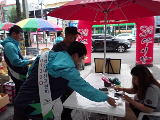 오산시선관위 직원들이 오색시장의 상인들에게 홍보용 사탕을 나눠주며 깨끗한 선거를 당부하고 있는 모습의 사진입니다