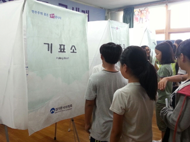 투표용지를 받고 기표소 앞에서 투표하기 위하여 줄을 서고 있는 학생들의 모습