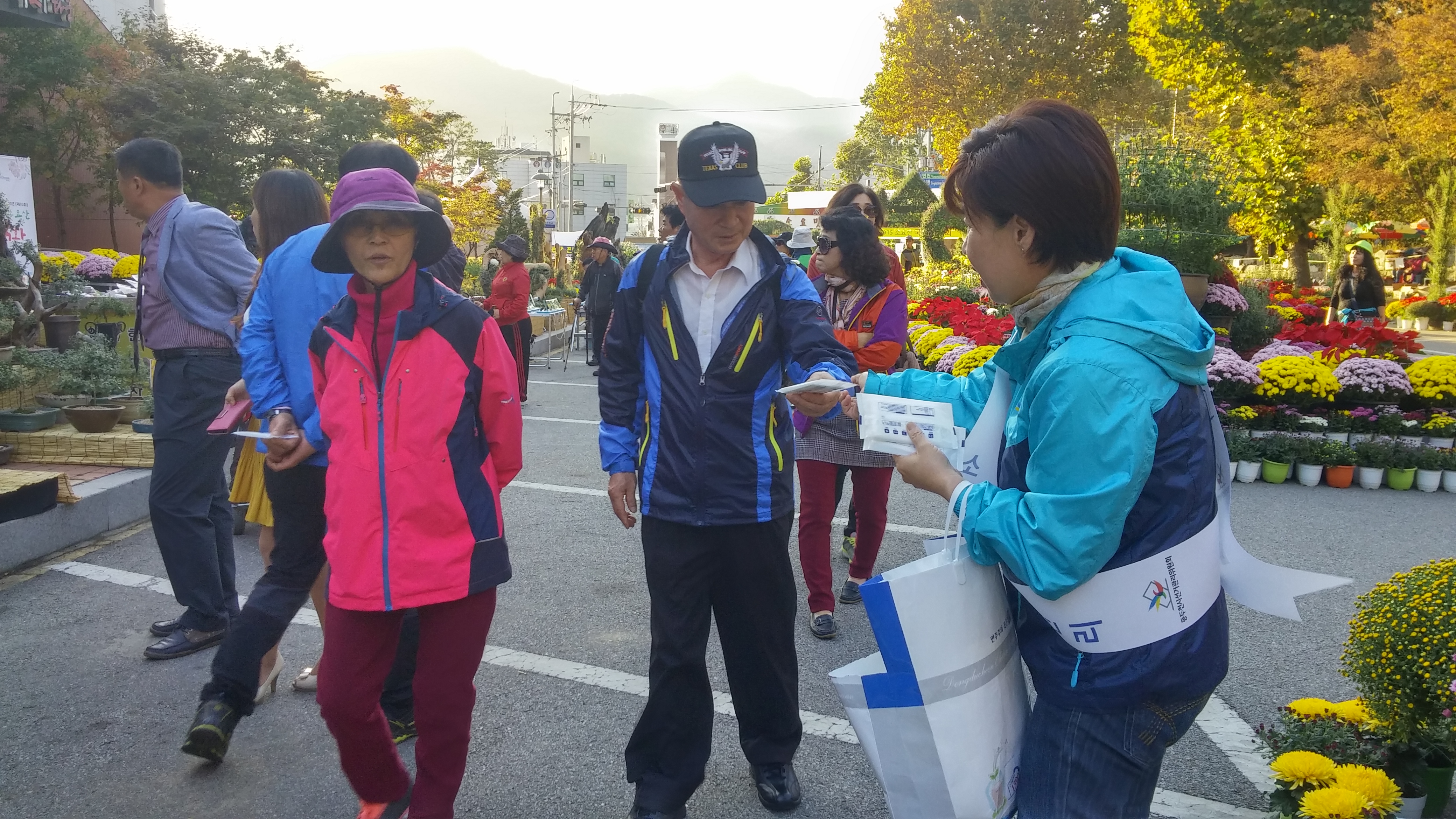 소요국화전시회장을 찾은 주민들에게 홍보용품을 나눠주며 과태료 포상금 및 정치후원금 관련 안내를 하고 있는 공정선거지원단의 모습입니다