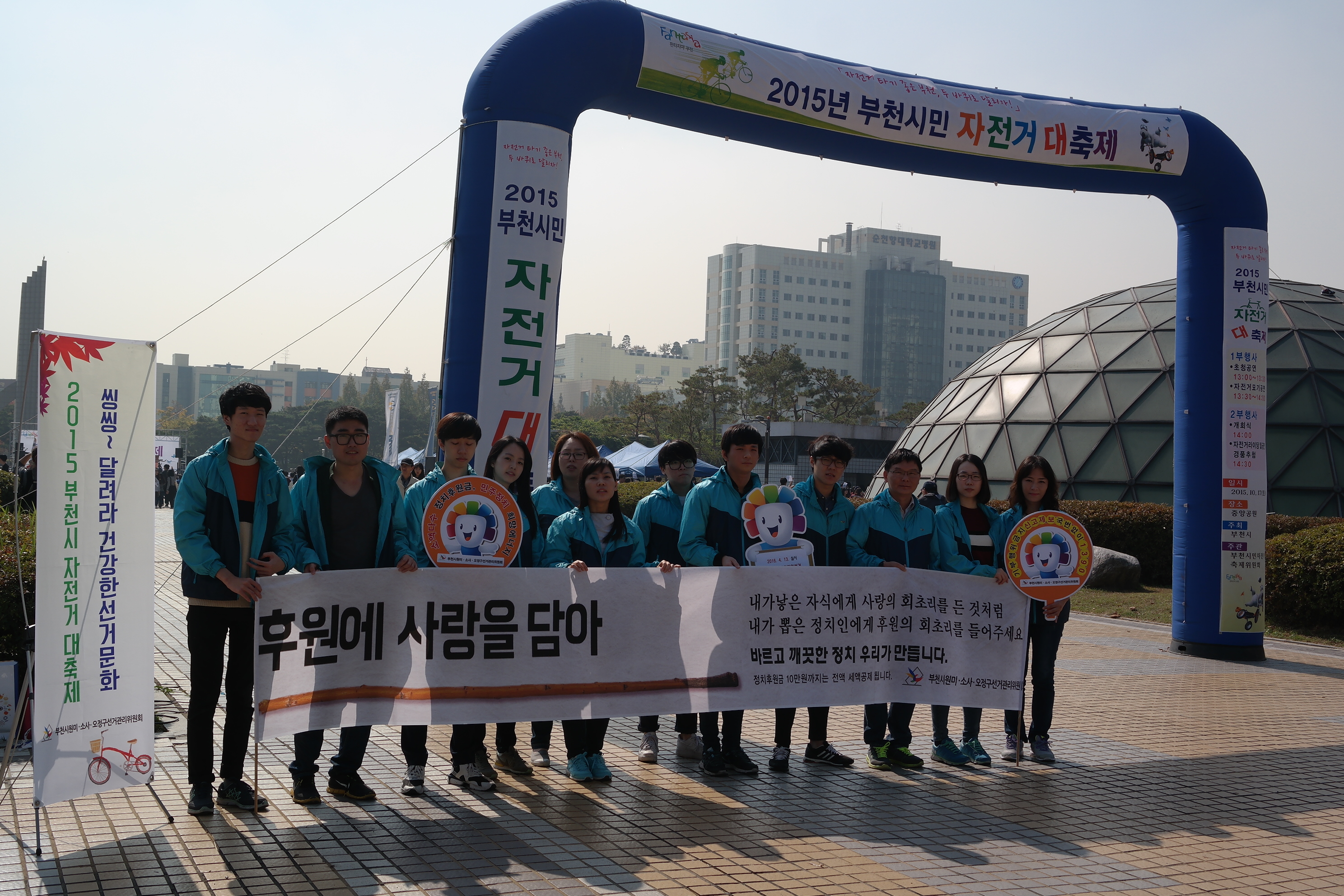 자전거축제장 입구에서 부천시 3개위원회가 피켓, 현수막, x-배너를 이용하여 홍보활동을 하고 있는 모습입니다.