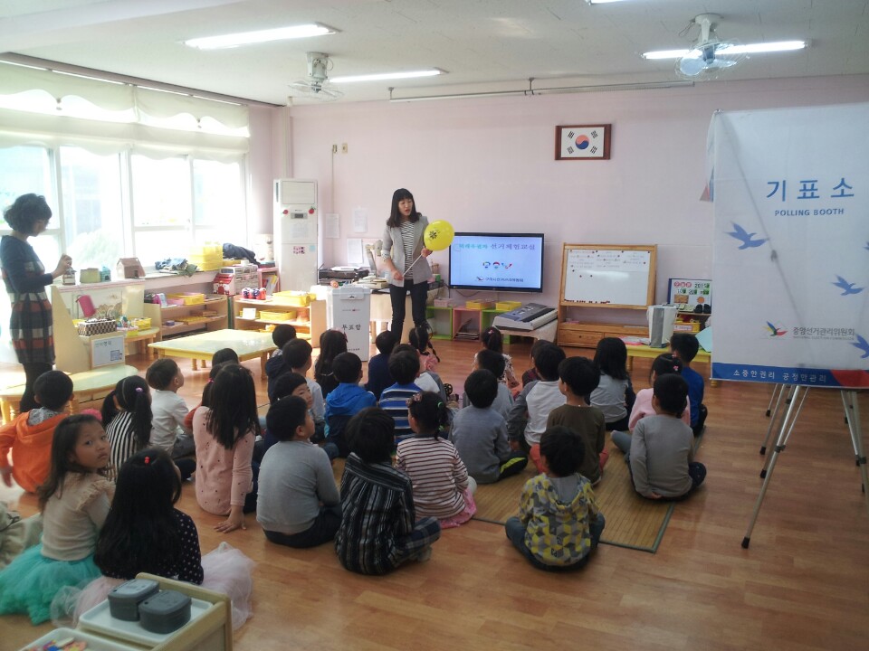 선거체험에 앞서 민주시민교육을 하고 있는 모습입니다. 질문에 먼저 답하는 어린이에게 '민주주의꽃선거' 풍선을 불어주었습니다.