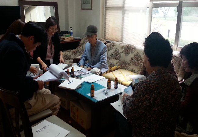 위원회 직원이 새터마을 모아미래도아파트 입주자대표회의실에서 아파트관리소장 등에게 공동주택선거 교재를 살펴보며 아파트선거 관련 내용을 설명하고 있는 모습