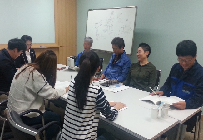  위원회 직원이 신봉센트레빌아파트 주민취미실에서 아파트관리소장 등에게 공동주택선거 교재를 살펴보며 아파트선거 관련 내용을 설명하고 있는 모습