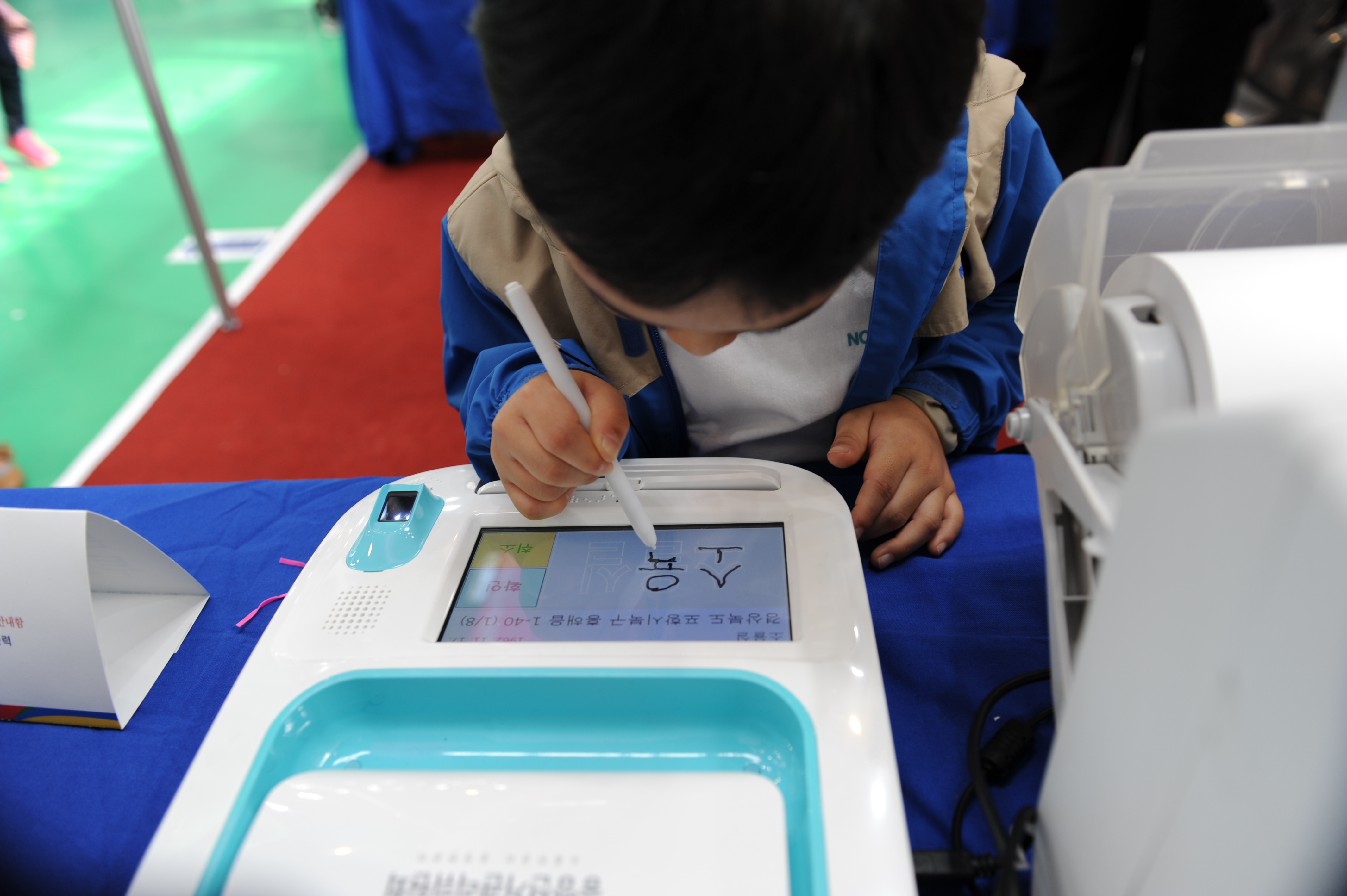 어린아이가 본인확인기에 서명하고 있는 모습
