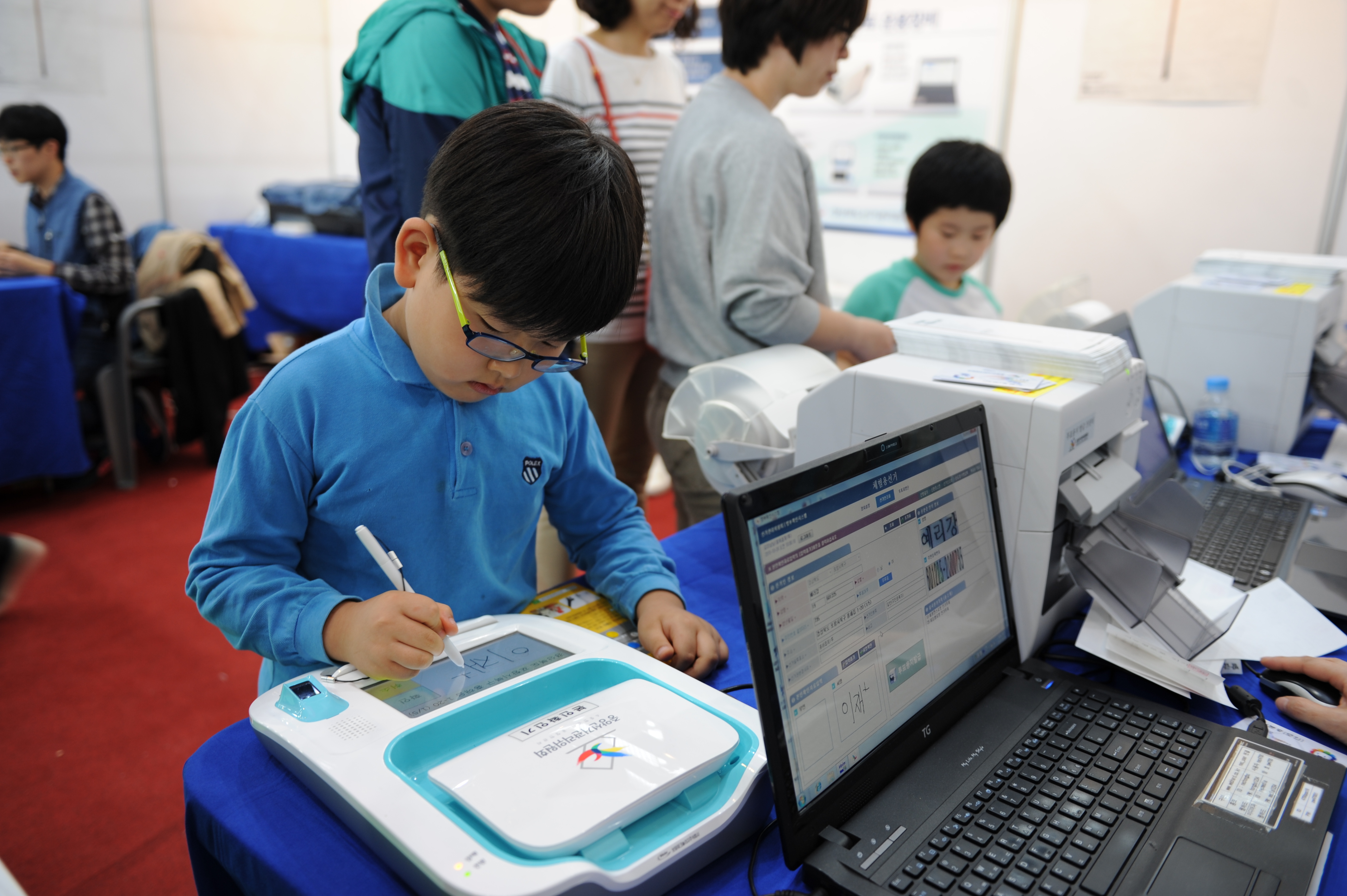 어린아이가 본인확인기에 서명하고 있는 모습