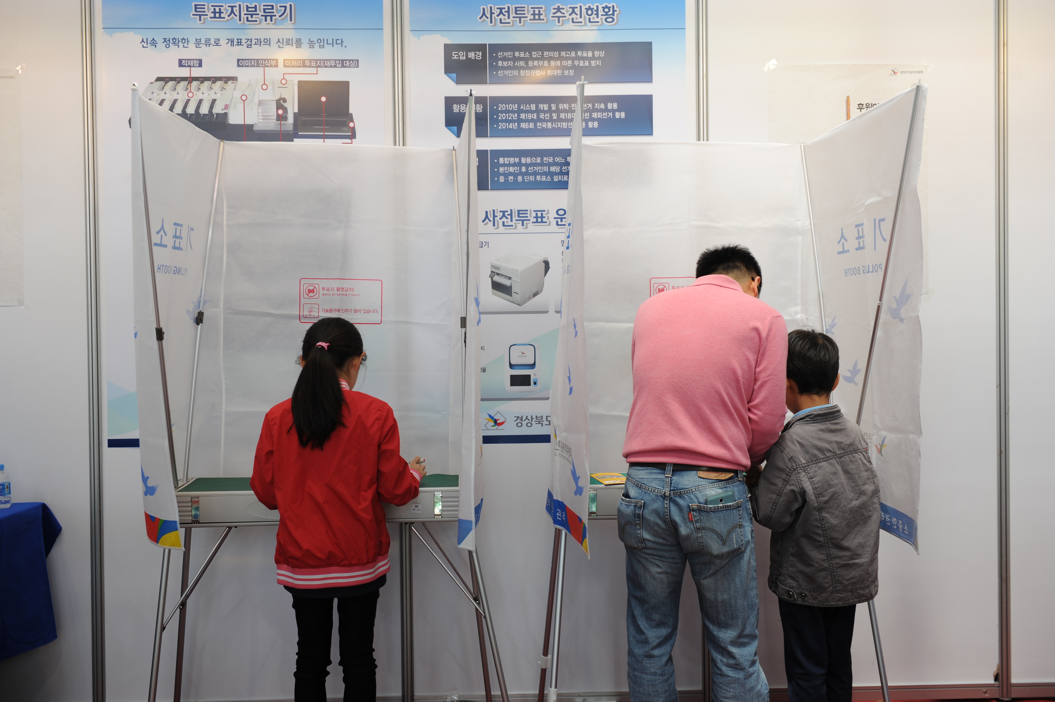 가족이 나란히 기표소에서 투표하는 모습