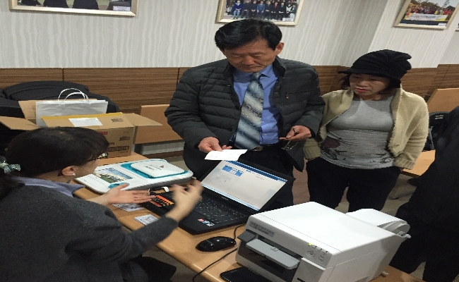 위원회 직원이 투표용지발급기에서 투표용지를 발급하고 사전투표에 관하여 설명하고 있는 모습