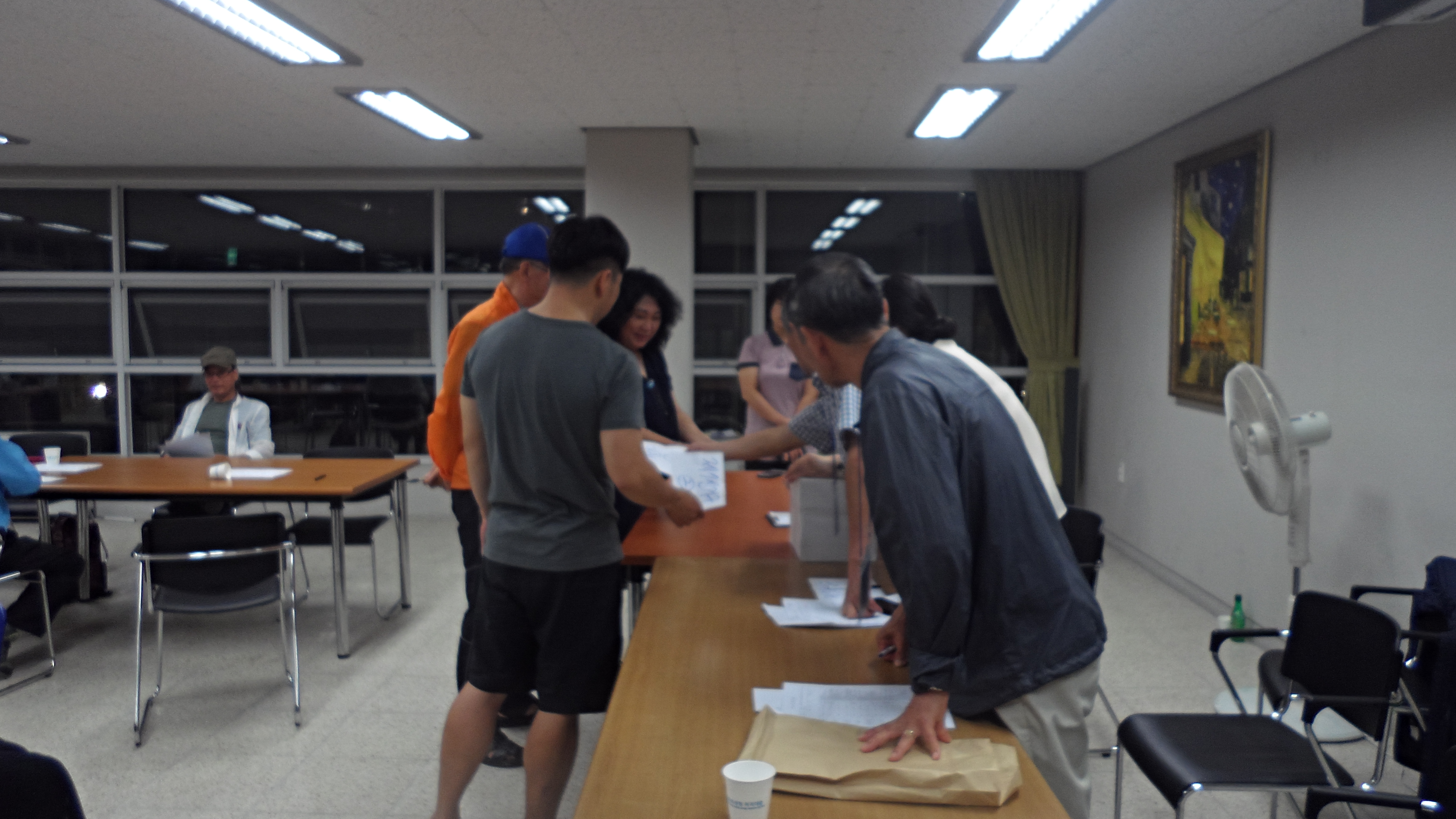 공택주택선거관리위원회 위원 등이 선거인명부를 확인하고 투표용지를 배부하는 모습의사진입니다.