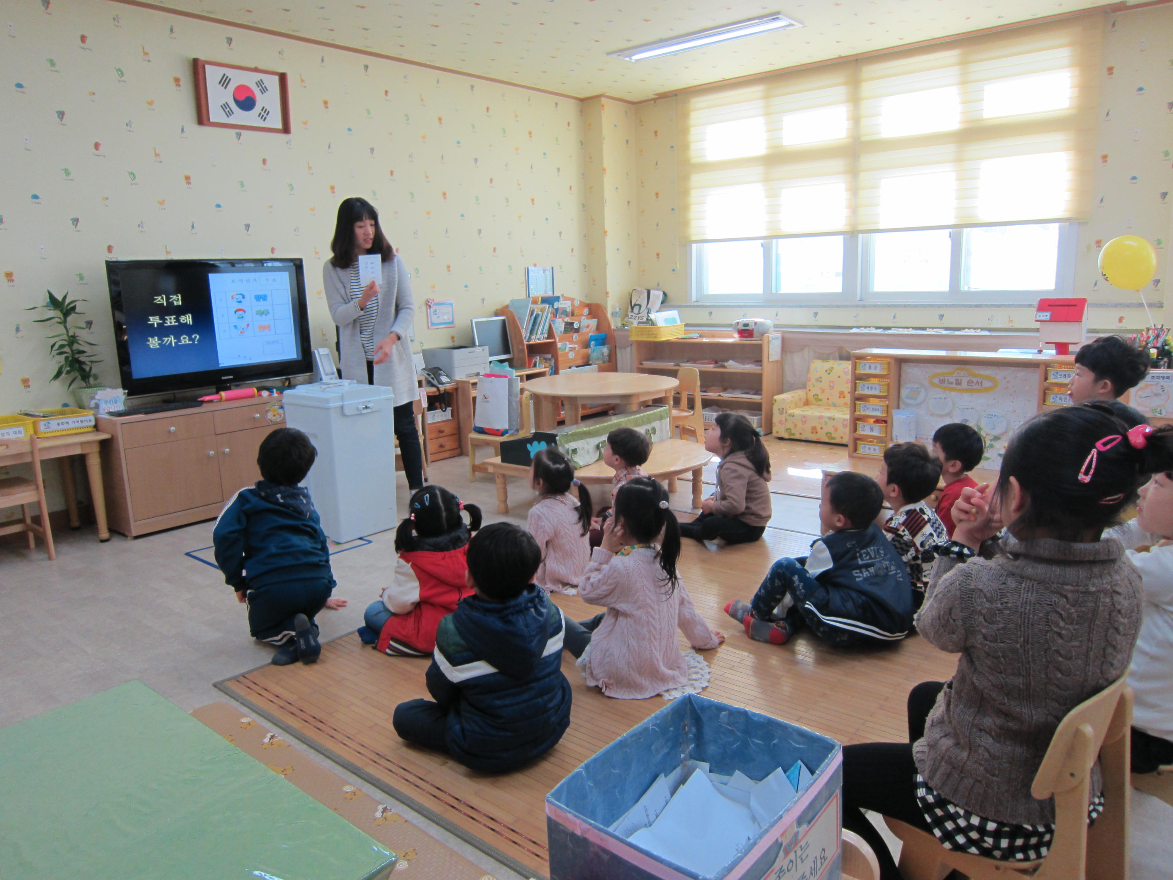 어린이들이 투표체험에 앞서 투표하는 방법에 대해 배우고 있습니다.