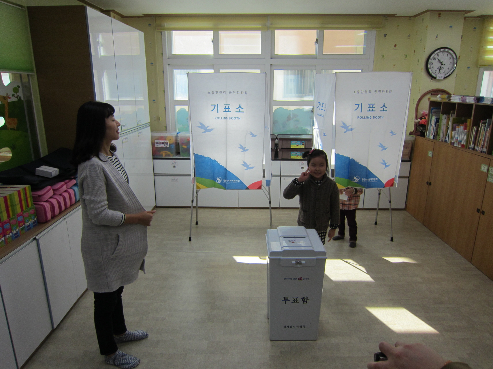 한 어린이가 투표함에 투표지를 넣고 인증샷을 찍고 있습니다.