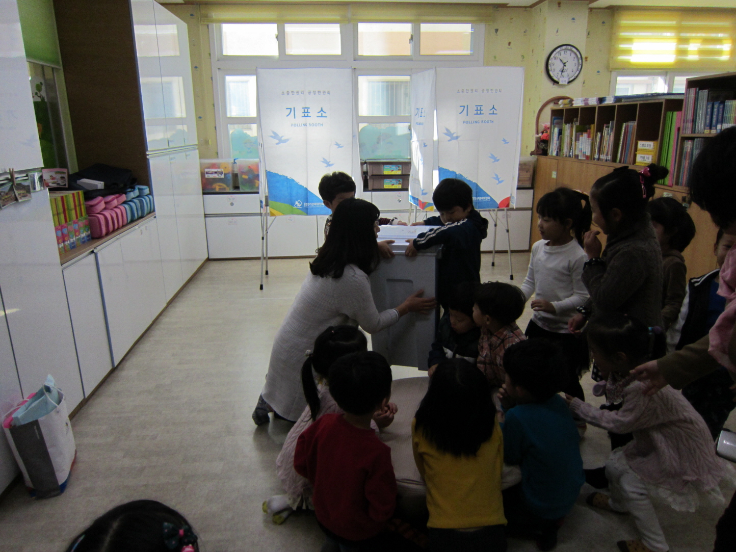 어린이들이 투표함을 여는 모습을 호기심어린 눈으로 지켜보고 있습니다.