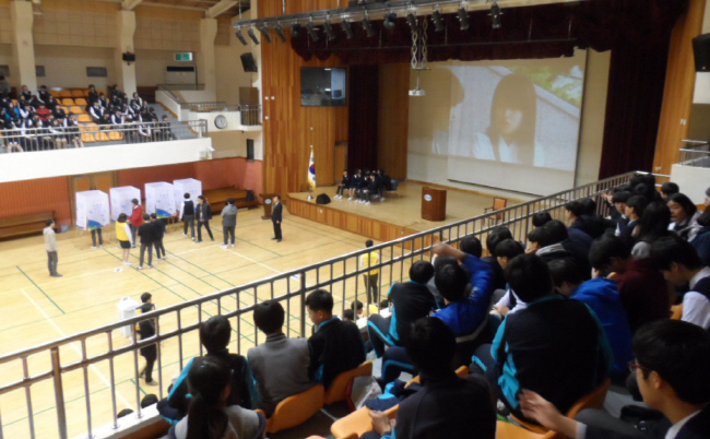 투표 현장 사진 학생들이 밀알관(체육관) 스탠드에 앉아 「우리들의 선택-선남선녀」영상을 시청하는 모습