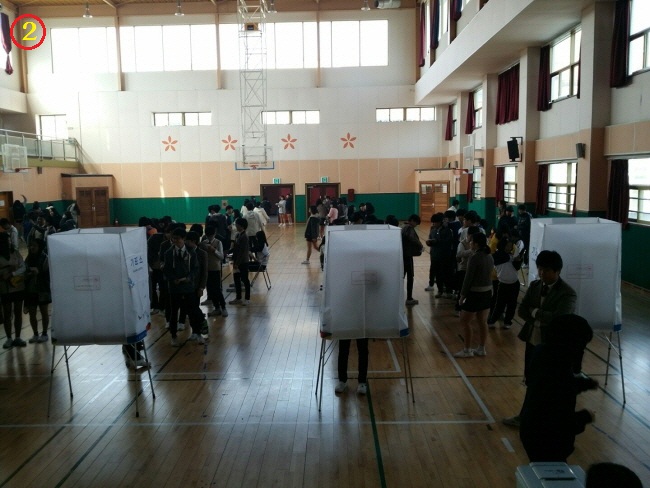 투표용지를 교부 받고 기표소 앞에서 투표하기 위하여 줄을 서고 있는 학생들의 모습