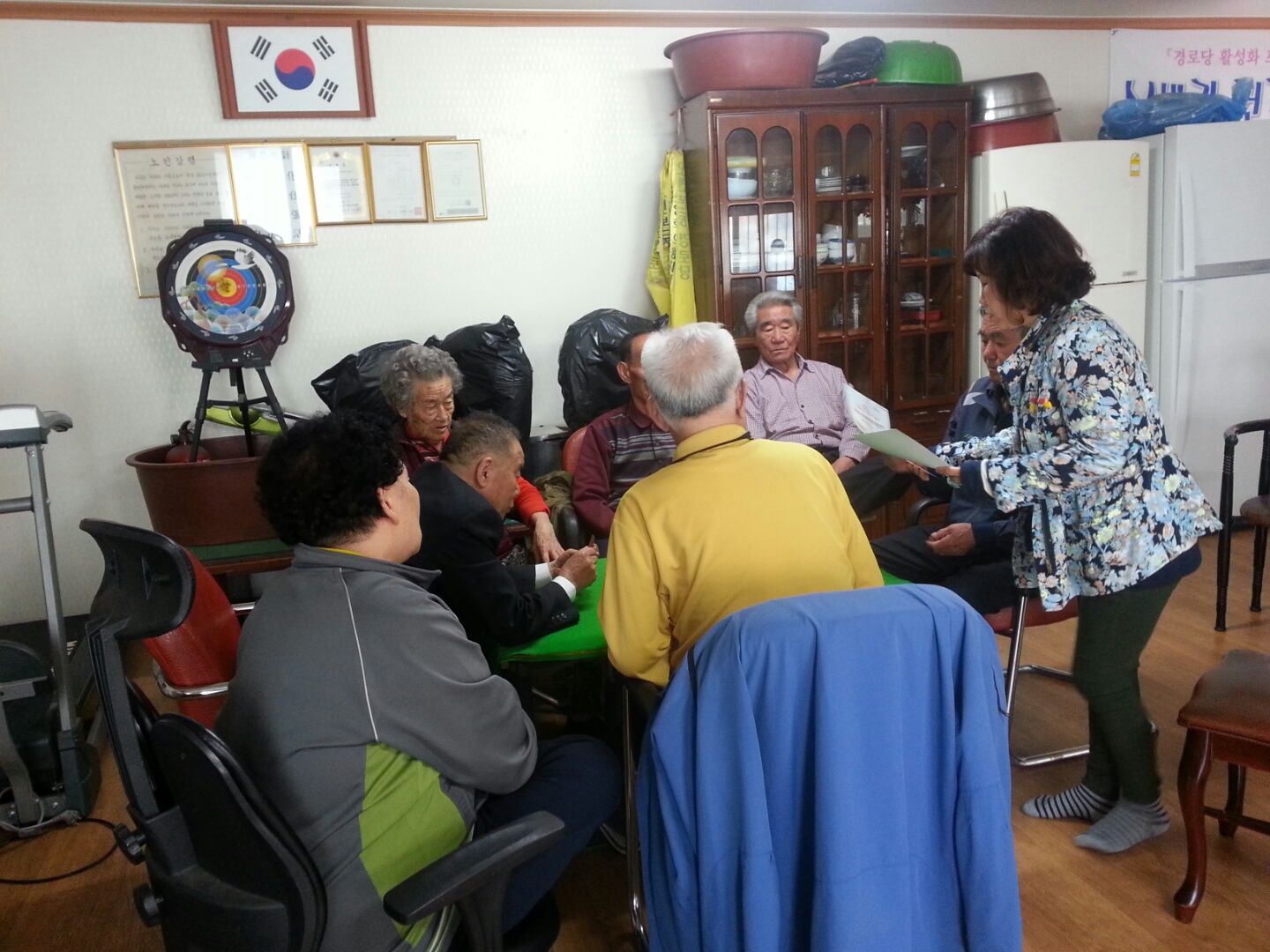 위원회 공정선거지원단이 매화아파트경로당에서 선거법 안내 및 홍보용품을 배부하고 있는 모습의 사진입니다.