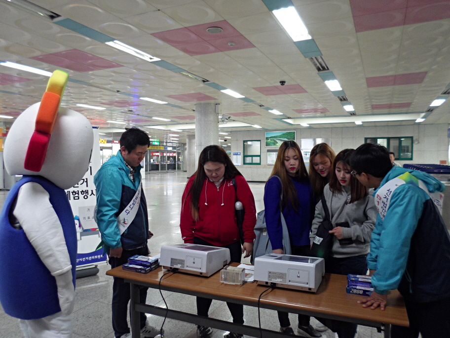 오산역을 찾은 시민들이 터치스크린 투표시스템을 이용하여 직접 모의투표 체험을 하고 있는 모습의 사진입니다