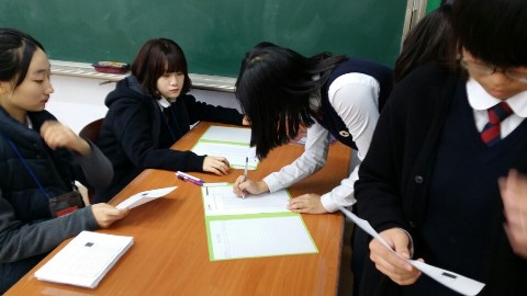 학생들이 선거를 하기 위하여 선거인명부에 본인확인을 하고 서명하는 모습