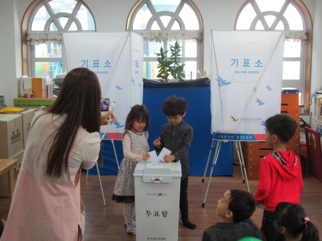 아이들이 투표함에 투표지를 넣는 모습