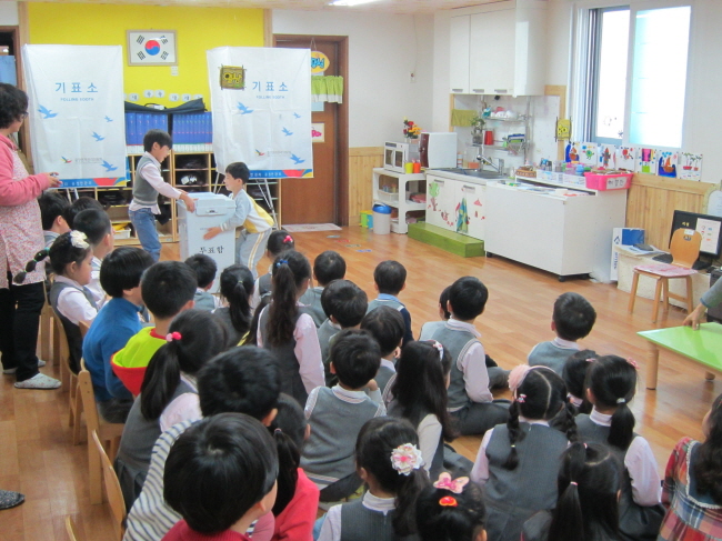 남자아이 두명이 투표함을 개표상 위로 옮기고 있는 모습