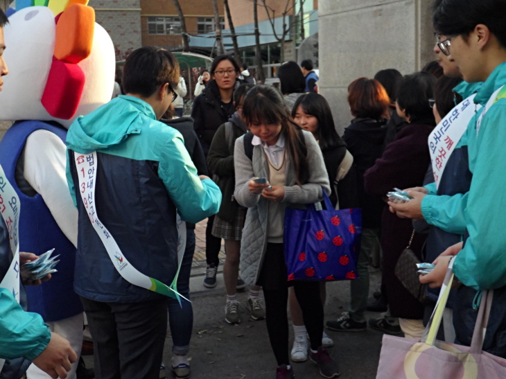 오산시선관위 직원들이 수능시험을 치른 학생들의 노고를 격려하고 투표참여를 당부하고 있는 모습의 사진입니다