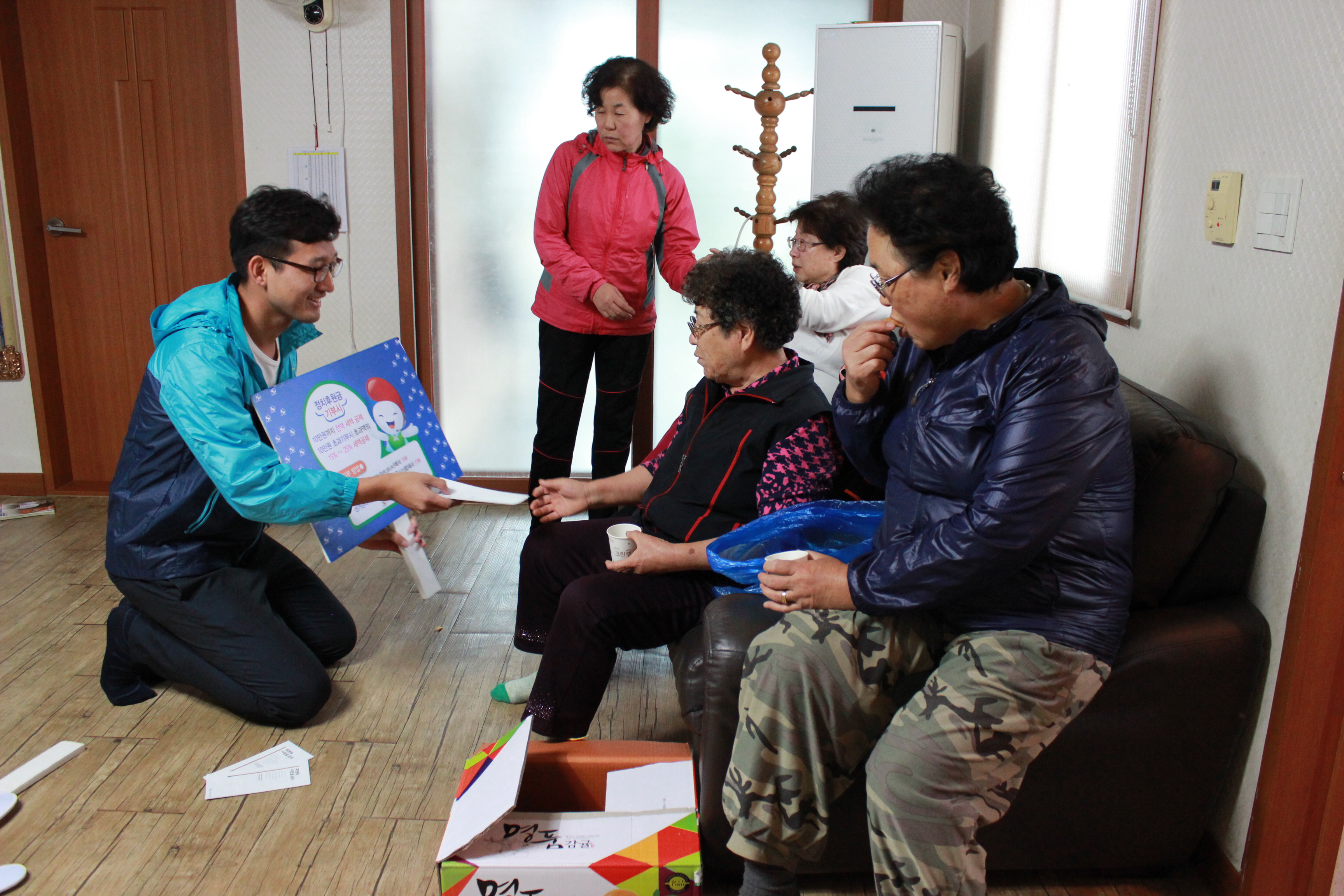 위원회 직원이 정치후원금 및 온라인 투표서비스 리플릿을 어르신들에게 배부하면서 주요 내용을 설명하는 모습