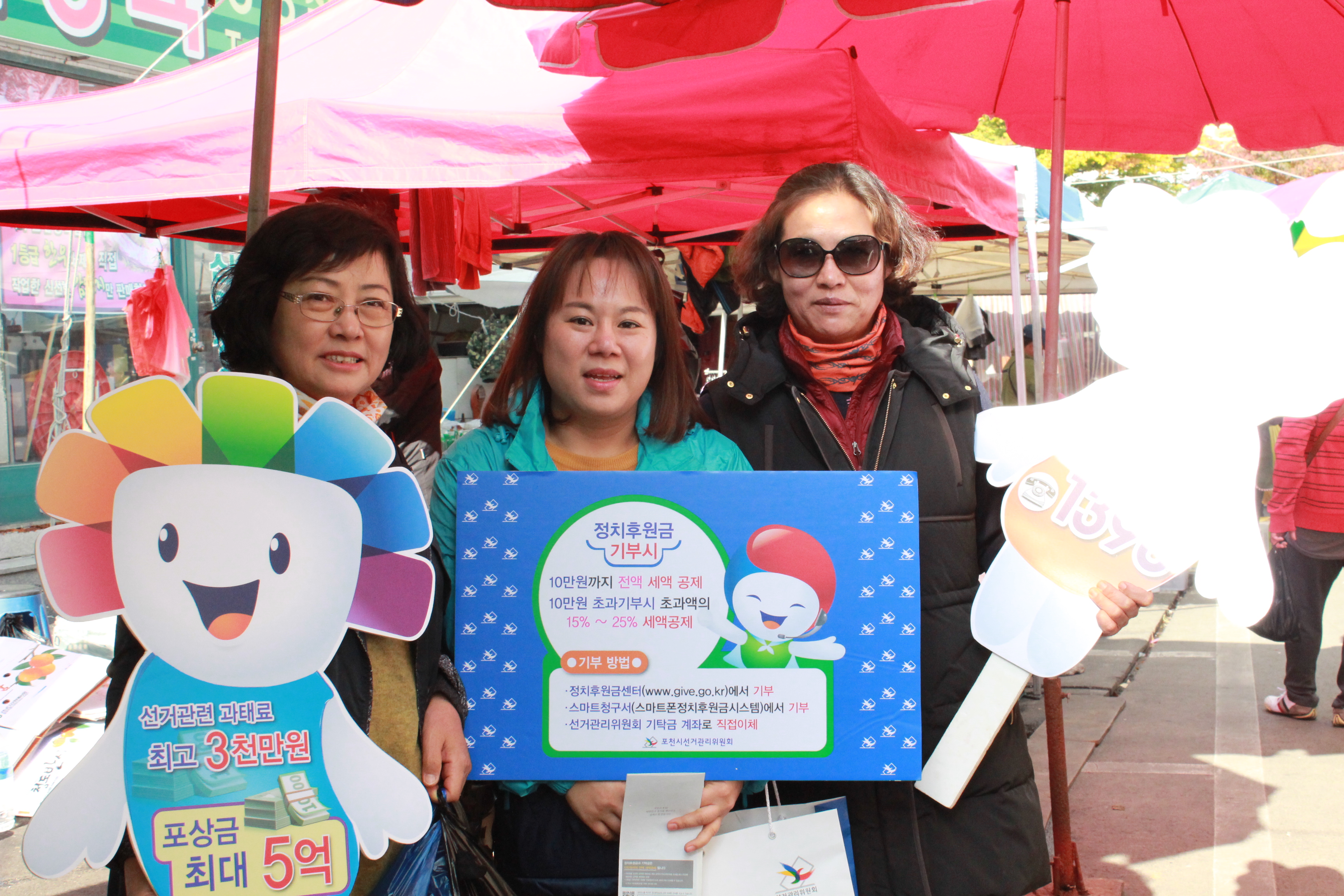전통시장을 이용하시는 주민들과 위원회 직원이 함께 홍보용 피켓을 이용하여 기념사진 촬영