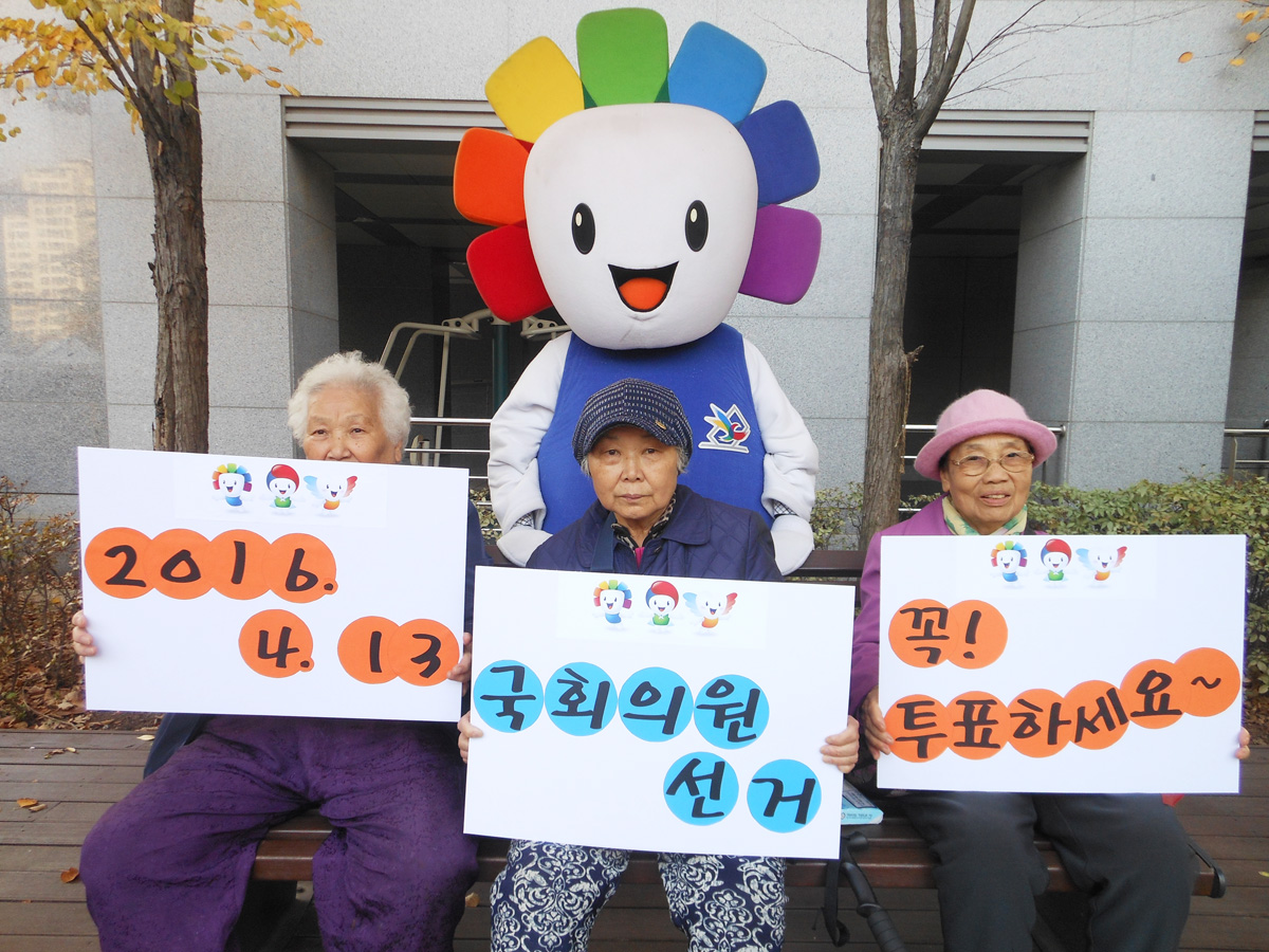 참참이와 함께 2015.4.13. 국회의원 선거 꼭 참여합시다.라는 내용의 피켓을 들고 포즈를 취하고 있는 어르신들의 모습