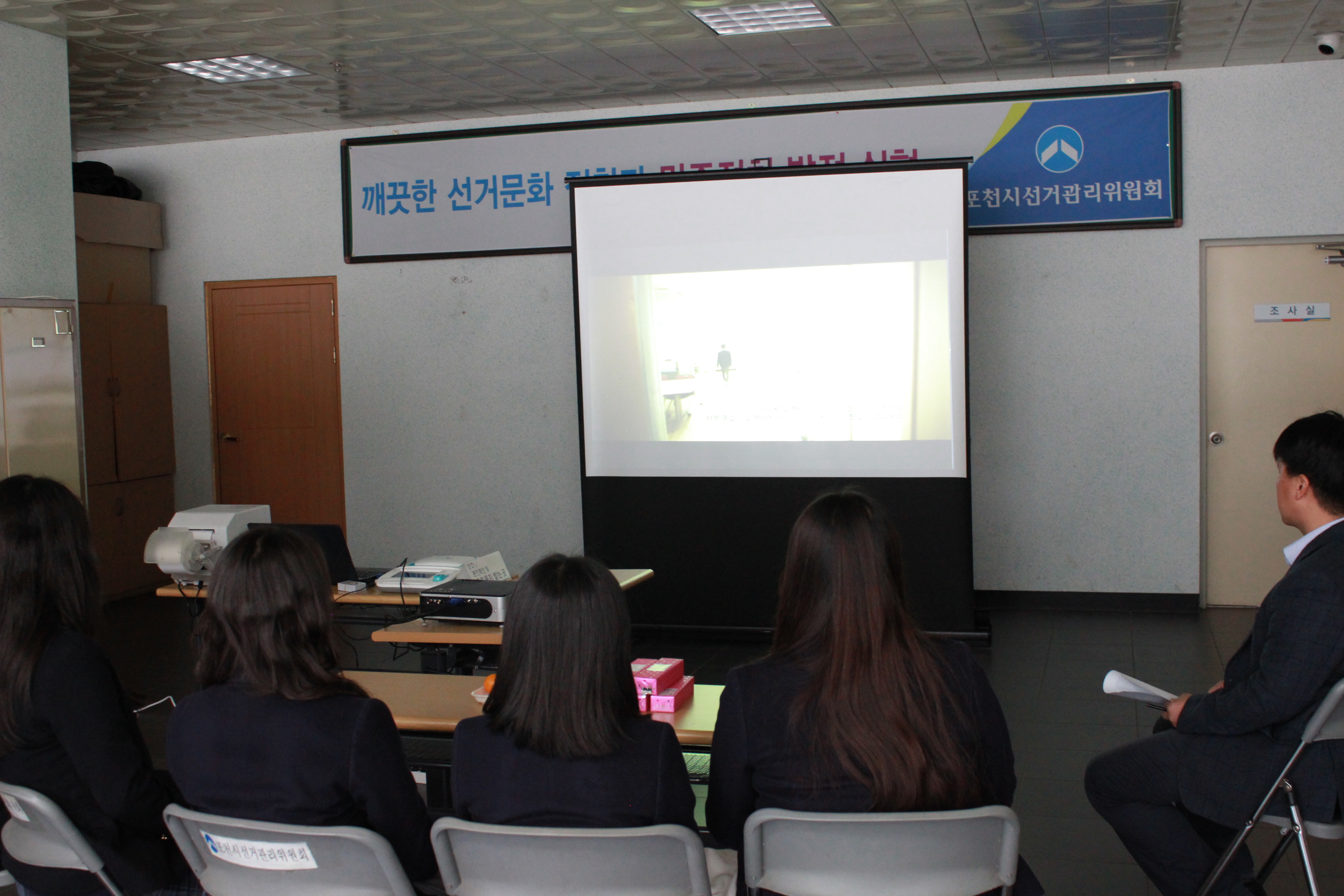 학생들이 위원회 홍보 영상과  선거의 중요성을 일깨우는 동영상을 시청하는 장면