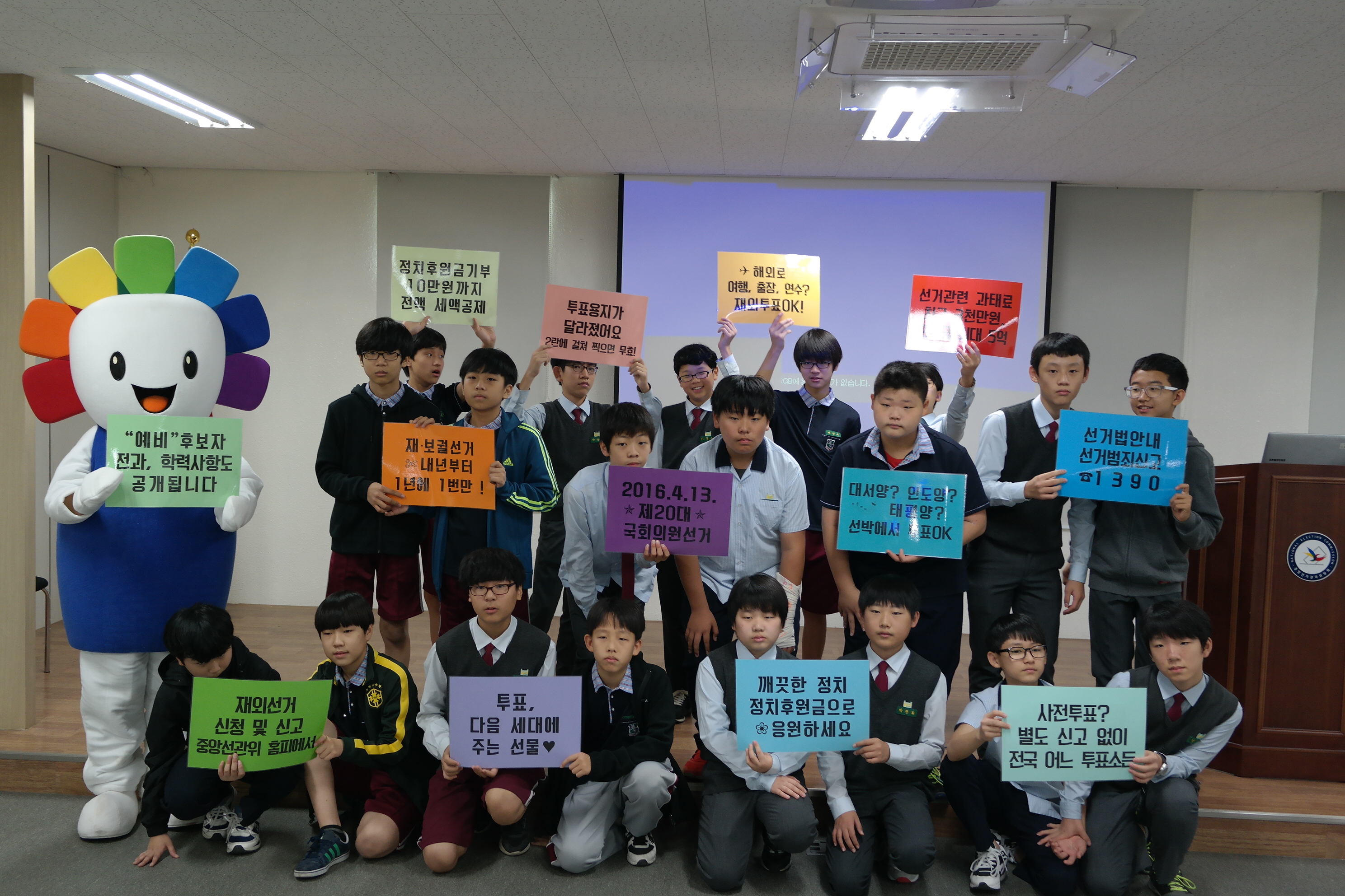 위원회를 방문한 학생들이 선거정보가 있는 플래카드를 들고 인증샷을 찍는 모습입니다.