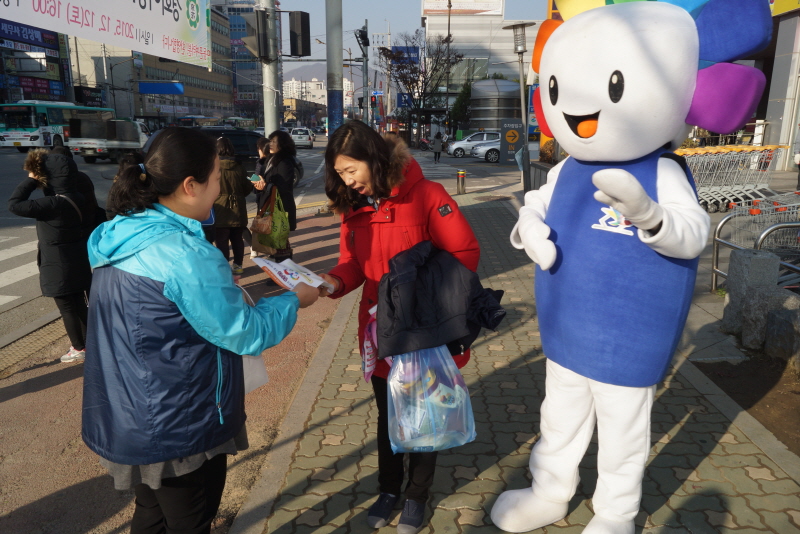 위원회 직원등이 지나가는 시민에게 정치후원금 및 이벤트 홍보전단을 배부하는 모습의 사진입니다.