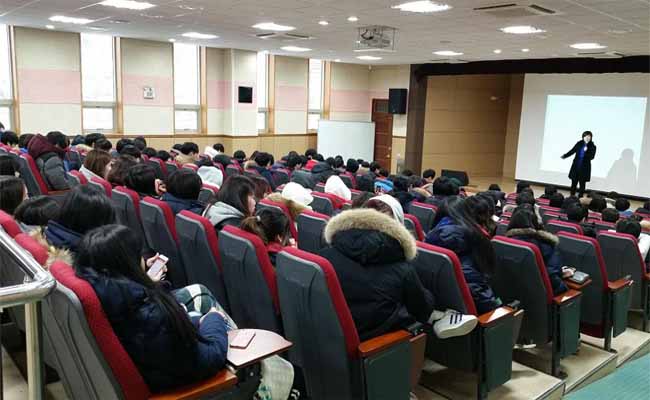 강사가 시청각실에 모여 앉아 있는 학생들을 대상으로 선거에 관하여 강의하고 있는 모습