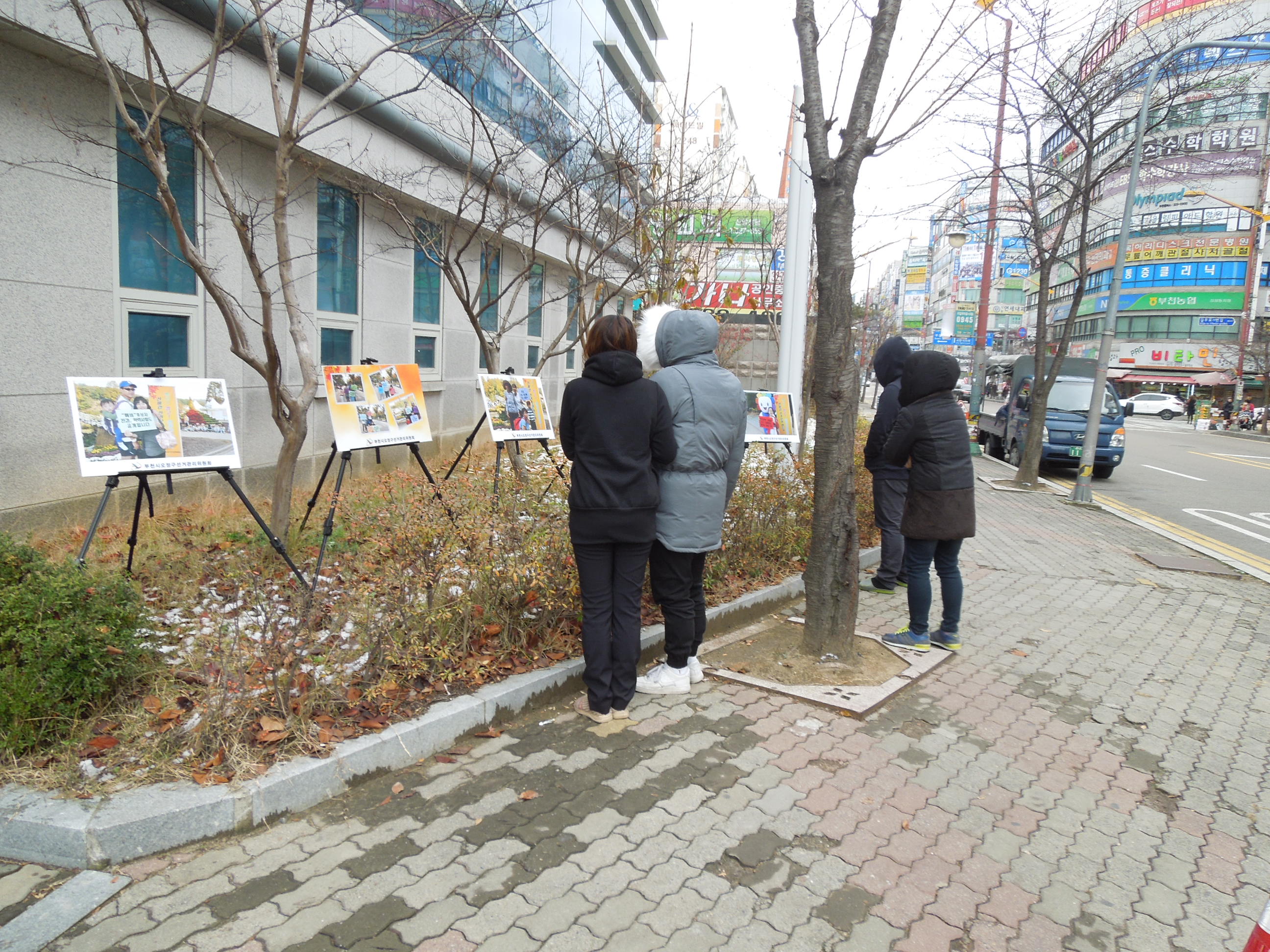 위원회 청사 앞에 전시된 사진작품을 시민들이 관람하고 있는 모습