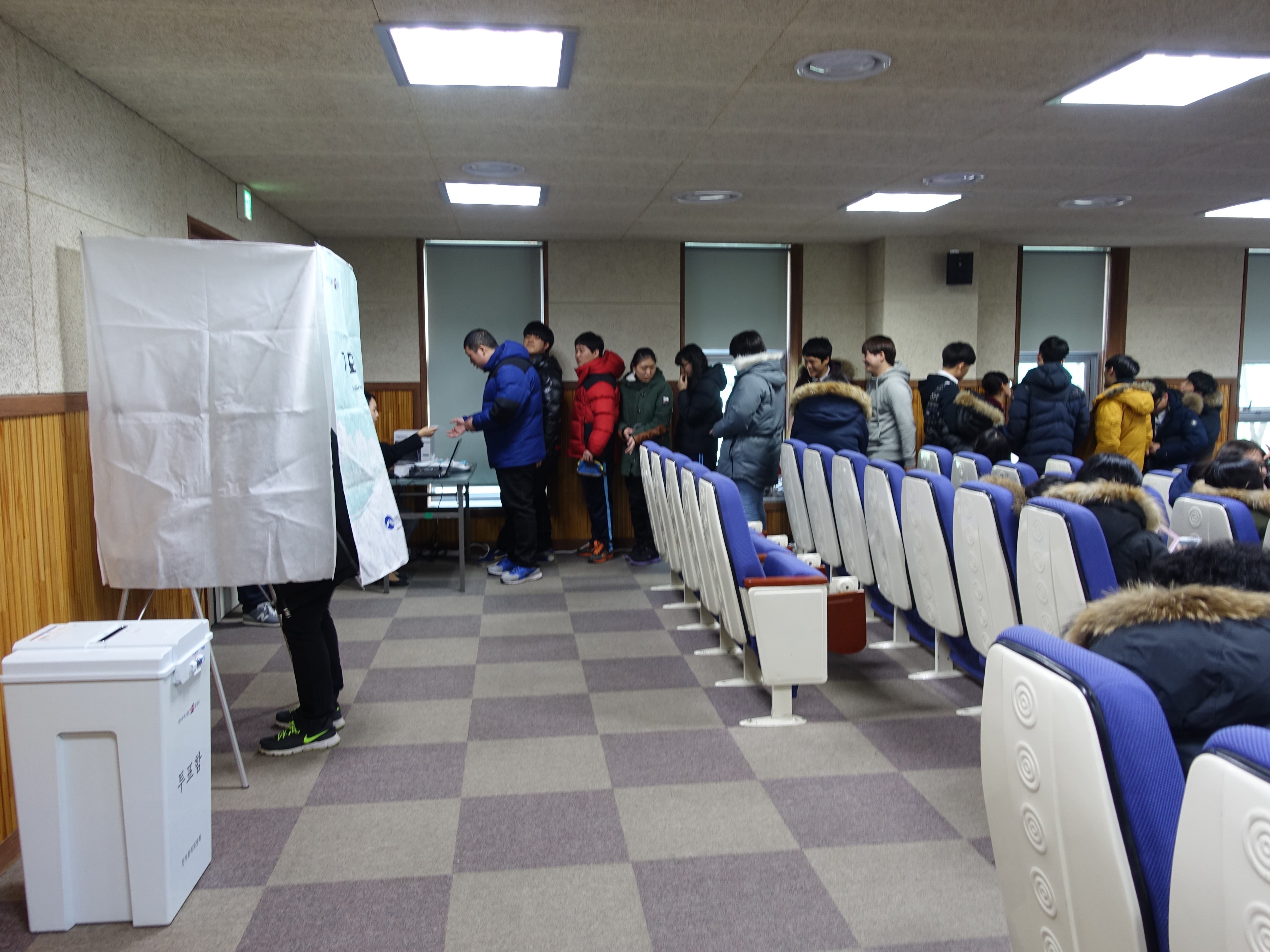 학생들이 투표용지 발급을 위하여 기다리는 모습 및 기표대 안에서 기표하고 있는 모습