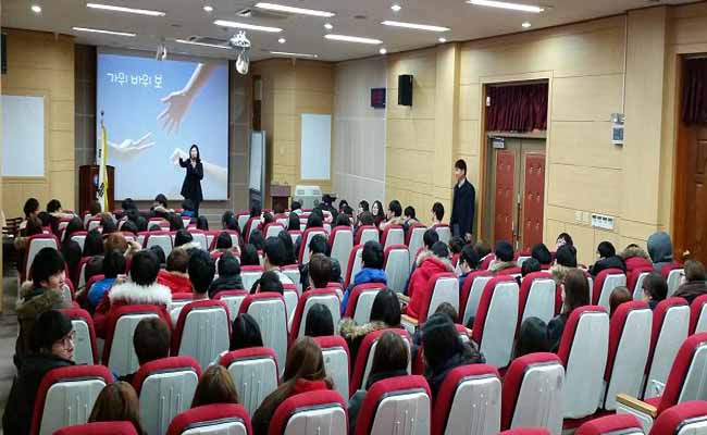 강사가 마이크를 들고 시청각실에 모여 앉아 있는 학생들을 대상으로 선거에 관하여 강의하고 있는 모습