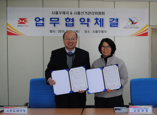 시흥시선관위 사무국장과 시흥우체국장이 업무협약을 체결하고 기념촬영을 하고 있다.